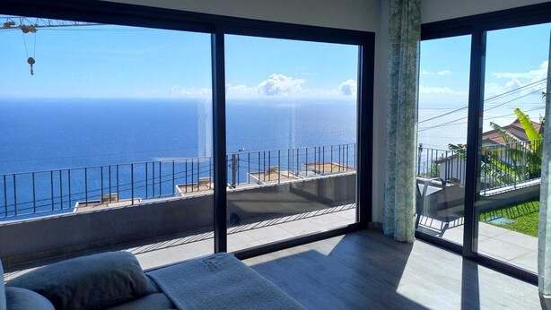 Ein geräumiges Zimmer mit großen Fenstern und Blick auf den Ozean.