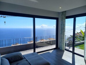 A spacious room with large windows offering a view of the ocean. - An apartment with a view of the sea, equipped with all the amenities you need for a relaxing vacation (Arco da Calheta)