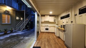 A narrow kitchen with a wooden floor, a refrigerator, a stove, and cabinets. There is a staircase leading to an upper level. - Golden Lodge (Tanah Rata)