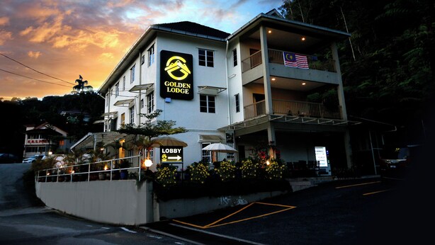A hotel named "Golden Lodge" with a lobby sign, a balcony with an American flag, and a view of the surrounding area. - Golden Lodge (Tanah Rata)
