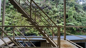 A staircase leading to a roofed area with a view of dense green foliage. - Golden Lodge (Tanah Rata)