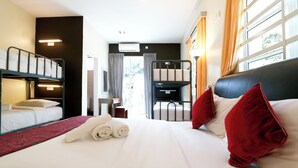 A hotel room with a bunk bed, a flat bed with red pillows, a red and black bed runner, and a TV in the corner. - Golden Lodge (Tanah Rata)