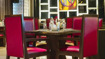 Un coin repas avec une table ronde, des chaises à revêtement rouge et un lustre.
