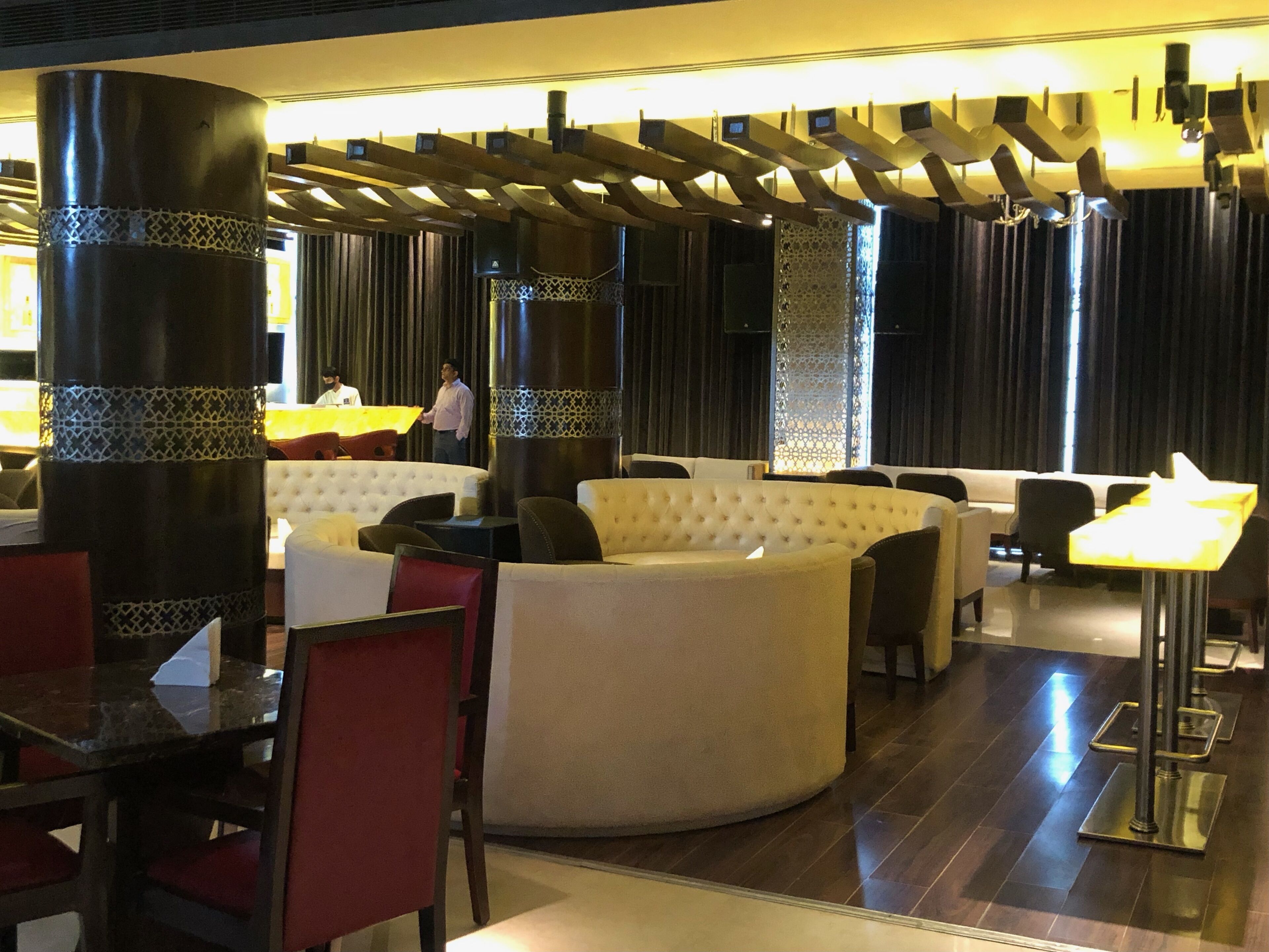 A modern lobby with a central seating area, high ceilings, and a decorative ceiling structure.