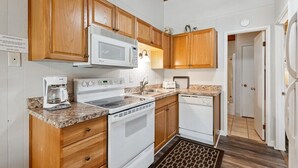 A kitchen with wooden cabinets, a microwave, stove, coffee maker, and a dishwasher. - Whitefish Lake Condo, 14BU, hillside! (Whitefish)