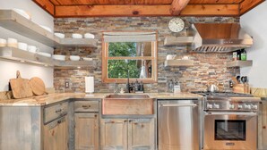 A kitchen with a rustic design, featuring a brick wall, wooden cabinets, and stainless steel appliances. - Sequoyah Lodge - 1.5 mi to DT (Fayetteville)