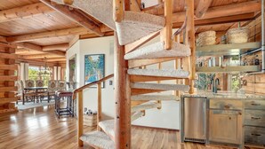 A wooden interior with a spiral staircase, a dining area, and a kitchen. - Sequoyah Lodge - 1.5 mi to DT (Fayetteville)