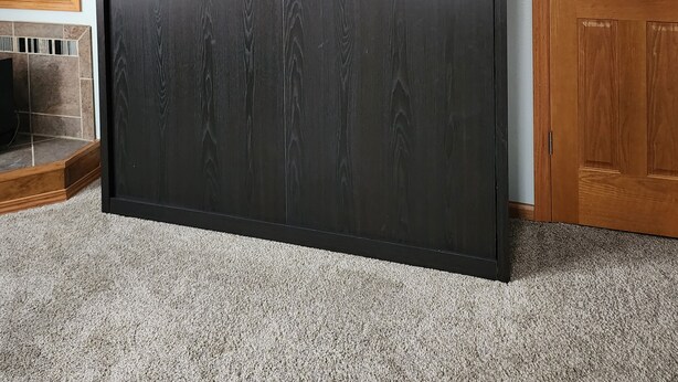 A room with a large wardrobe, a wooden door, and a tiled floor.