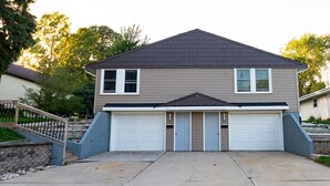 A two-story house with a garage, a front porch, and a stone staircase leading to the entrance.