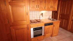 A kitchen with wooden cabinets, a tiled backsplash, a stove, an oven, a dishwasher, and a sink. - 150m from ski slopes, 1st floor, view ski slopes, balcony, tv, 34m², Les Saisies (Les Saisies)
