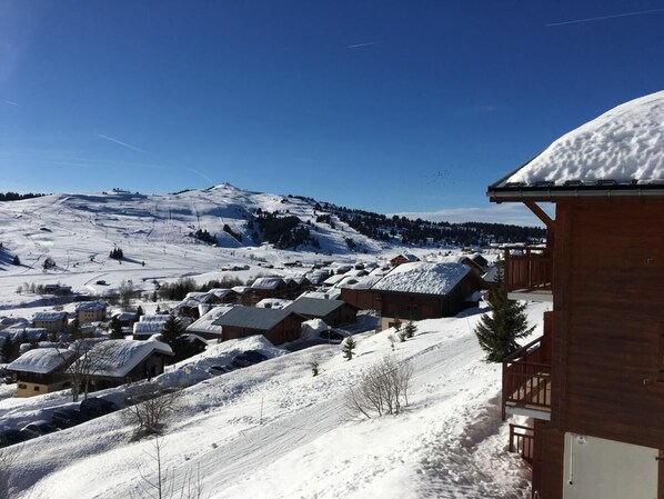 A snow-covered village with wooden buildings and a mountain in the background.