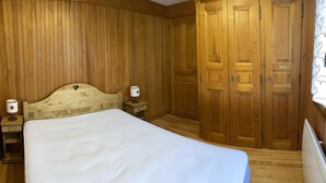 A wooden-paneled bedroom with a bed, two bedside tables, and a wardrobe. - 150m from ski slopes, 1st floor, view ski slopes, balcony, tv, 34m², Les Saisies (Les Saisies)