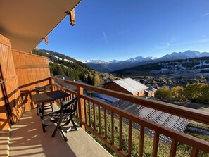 A balcony with a wooden railing overlooking a mountainous landscape.