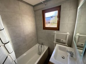 A bathroom with a bathtub, a sink, and a window with a view.
