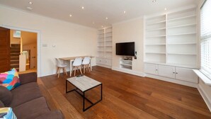 Ein modernes Wohnzimmer mit einem braunen Sofa, einem Couchtisch, einem an der Wand befestigten Fernseher und eingebauten Regale.