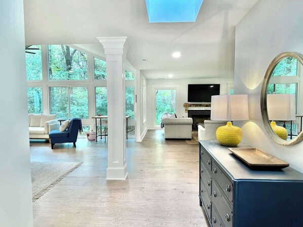 A spacious living area with a high ceiling, large windows, a fireplace, and a modern entertainment unit.