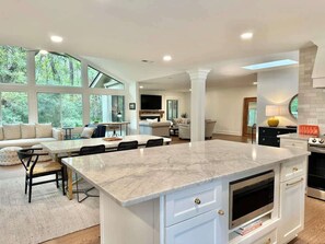 A spacious kitchen with a large island, white cabinetry, and a dining area with a sofa and chairs.