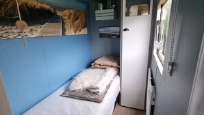Een kleine kamer met een bed, een bureau en een raam.