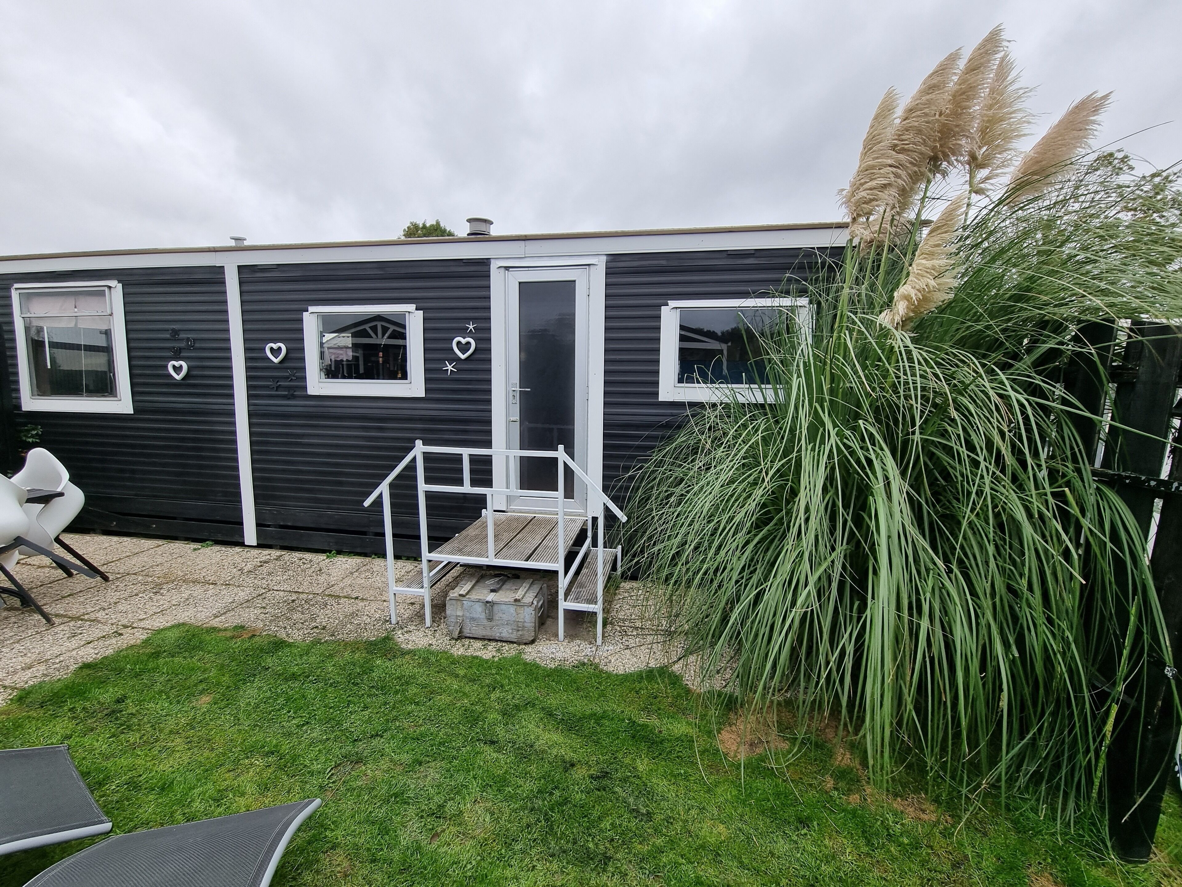 A modern, compact mobile home with a small porch and a window.