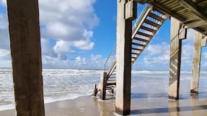 Een strand met een houten pier en een trap naar een overdekt gebied.