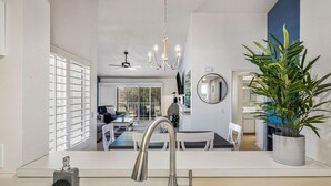 A modern kitchen with a large island, stainless steel appliances, and a potted plant.