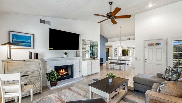 A spacious living room with a fireplace, a television, and a ceiling fan.
