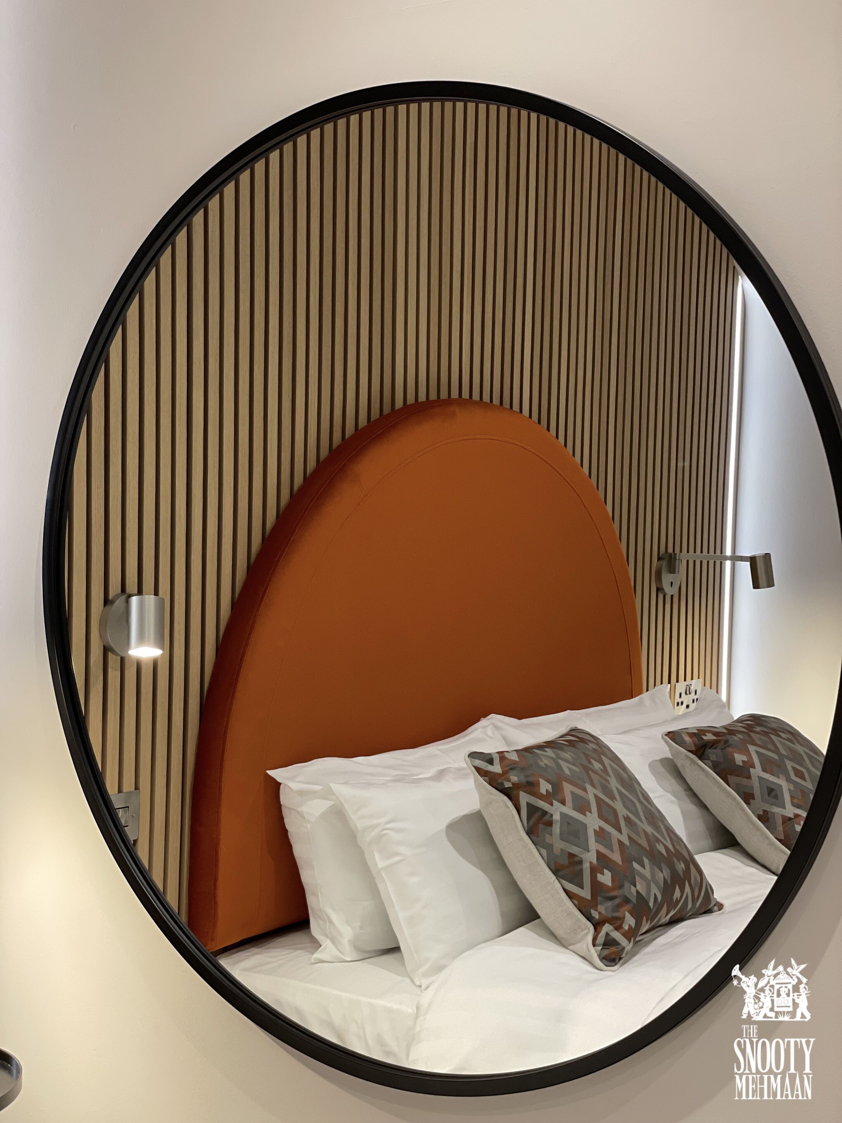 A circular bed with a curved headboard, white bedding, and patterned pillows.