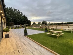 A well-maintained outdoor area with a paved walkway, picnic tables, and neatly trimmed grass.