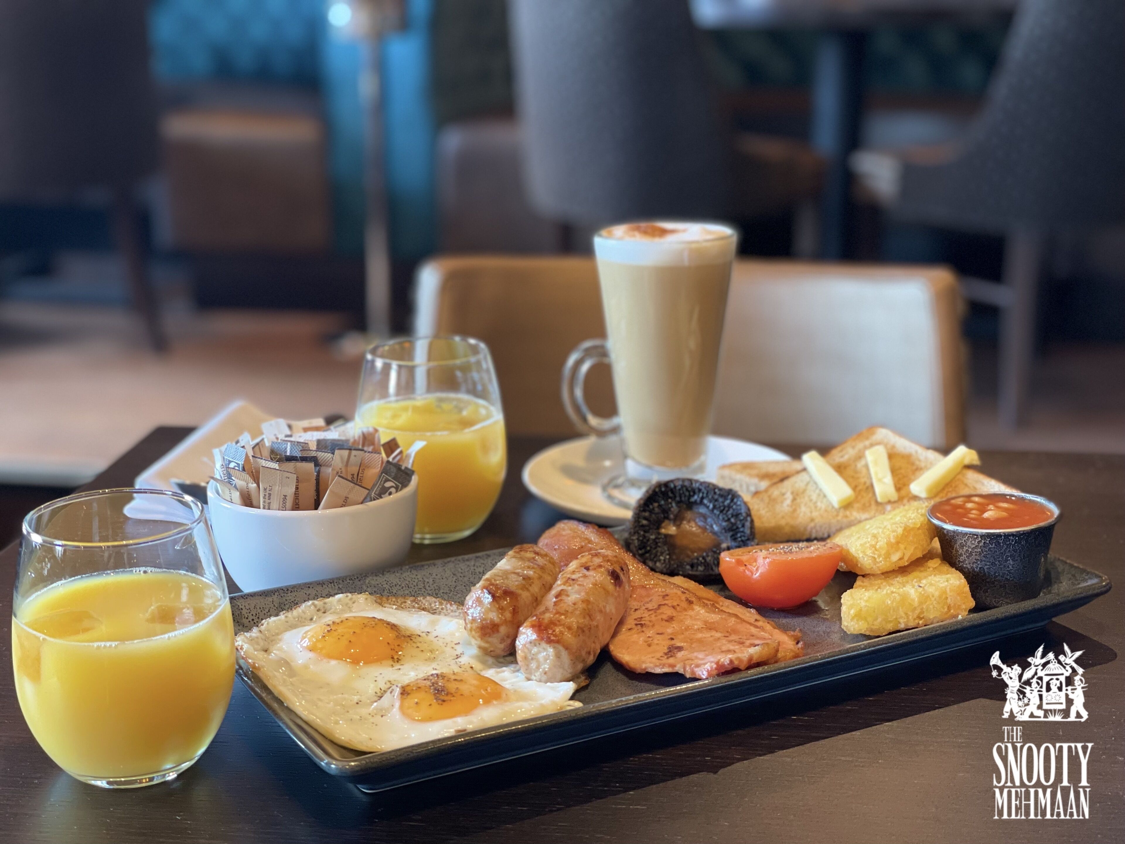 Un plateau de petit-déjeuner avec des œufs, des saucisses, des toasts et une boisson au café.