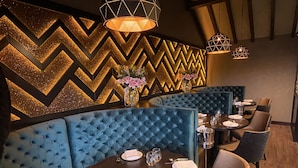 A restaurant with blue upholstered booths, a zigzag patterned wall, and a chandelier. - The Boutique Hotel by The Snooty Mehmaan (Faringdon)