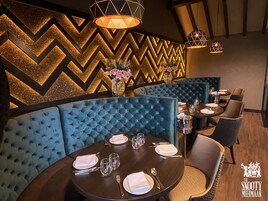 Un restaurante con asientos tapizados en azul, un muro con diseño en zigzag y una araña.