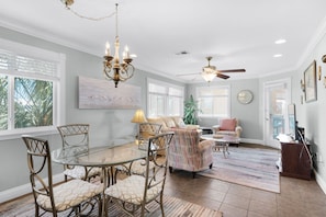 A spacious living room with a glass dining table, comfortable seating, a ceiling fan, and a large window with blinds. - ☀️Sound Front Complex-Awesome Amenities-2BR Sunset Harbor Palms 2-301☀️ (Navarre Beach)