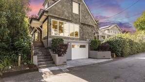 Une maison à deux étages, dotée d’un toit à forte pente, d’un porche à l’avant et d’un garage.