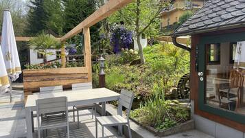 A patio with outdoor seating, a wooden pergola, and a garden with various plants and flowers.