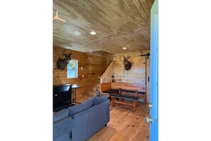 Cozy cabin-style interior with a wooden staircase, comfortable seating area, and TV.