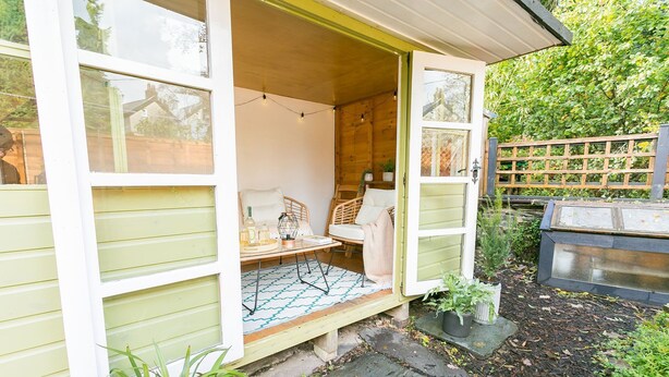 Een gezellig buiten zitgedeelte met een tafel en stoelen, een kleine tuin en een houten omheining.