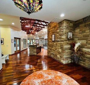 Eine geräumige Lobby mit Holzboden, einer Wand als Steinakzent und einer Decke aus Buntglas, sowie einer zentralen Insellounge.