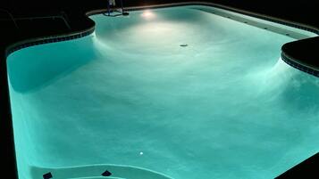 Une piscine avec un panier de basketball et un bord carrelé.