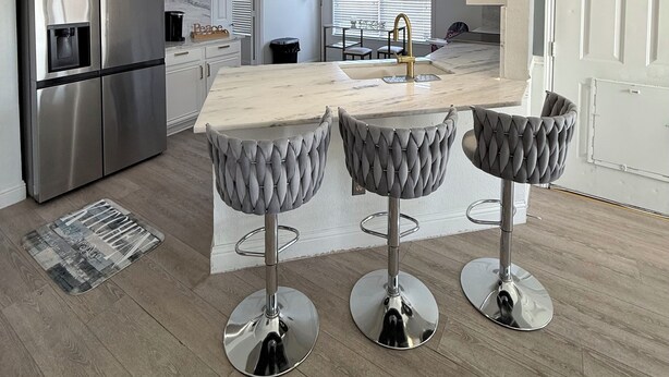 A modern kitchen with a stainless steel refrigerator, a marble countertop island, and three bar stools. - Luxurious home /Pool/GameR/BBQ/kingbed/legacyW/Frisco (plano)