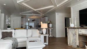 A spacious living area with a white sofa, a coffee table, and a TV on a wooden cabinet.