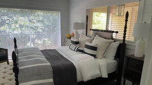A bedroom with a bed, bedside tables, a chair, and a window with blinds.