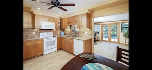 Enjoy cooking in this kitchen with a large island, stove, and microwave, offering a view of the outdoors through large windows.