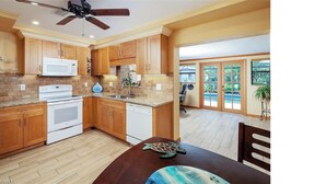 A kitchen with wooden cabinets, a white stove, and a ceiling fan.