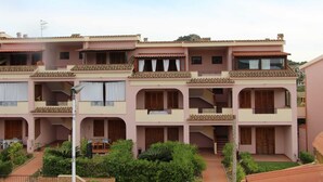 Un edificio de varios pisos con balcones, un patio interior y un pequeño jardín.