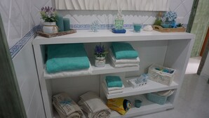 Un baño con tocador blanco, toallas color turquesa, una planta pequeña y un jabonera decorativa.