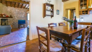 A rustic dining area with a stone fireplace, wooden beams, and a stone wall.