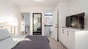Un dormitorio moderno con cama, televisor y vestidor.