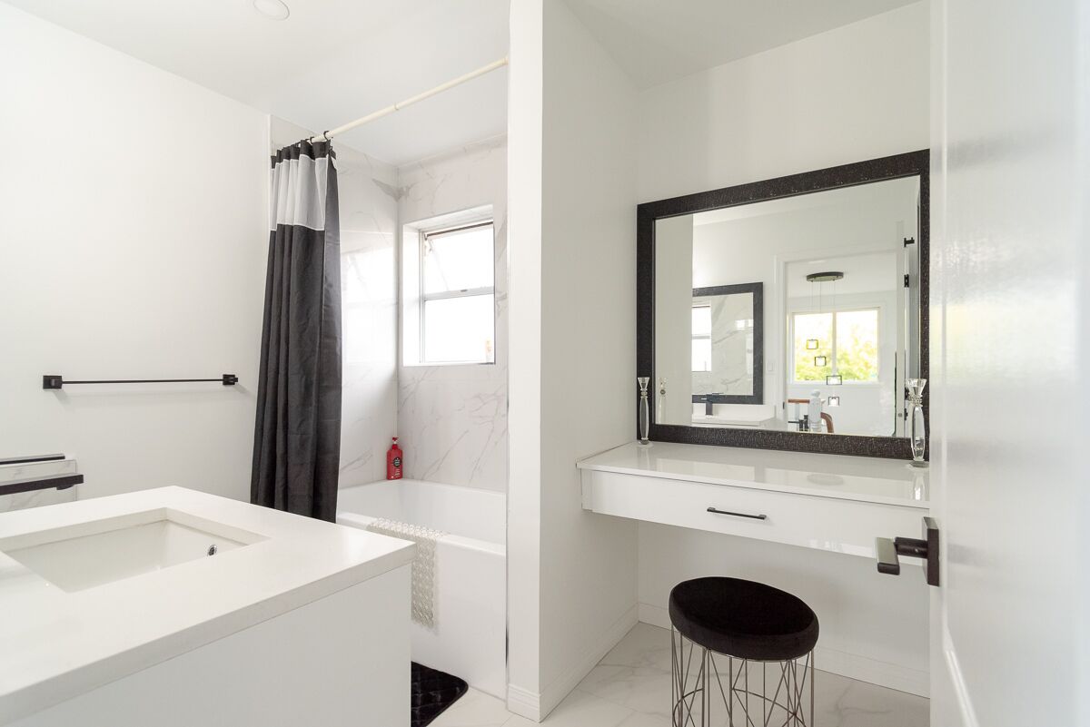 Un bagno moderno con uno specchio grande, una vasca e un water.