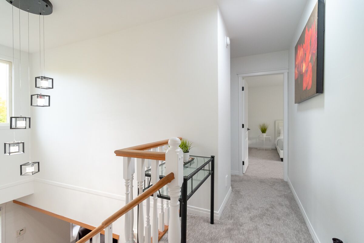 A staircase with a glass railing, white walls, and a framed picture on the wall.