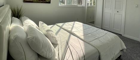 Une chambre à coucher avec un lit, un ventilateur de plafond, une fenêtre, une porte et un tableau accroché au mur.